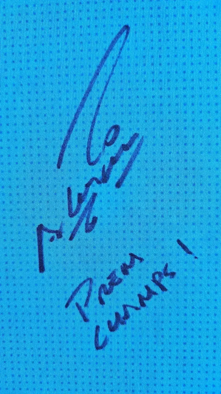 Close-up of Sergio Agüero's signature on blue Manchester City shirt fabric. Includes 'Premiership' text.
