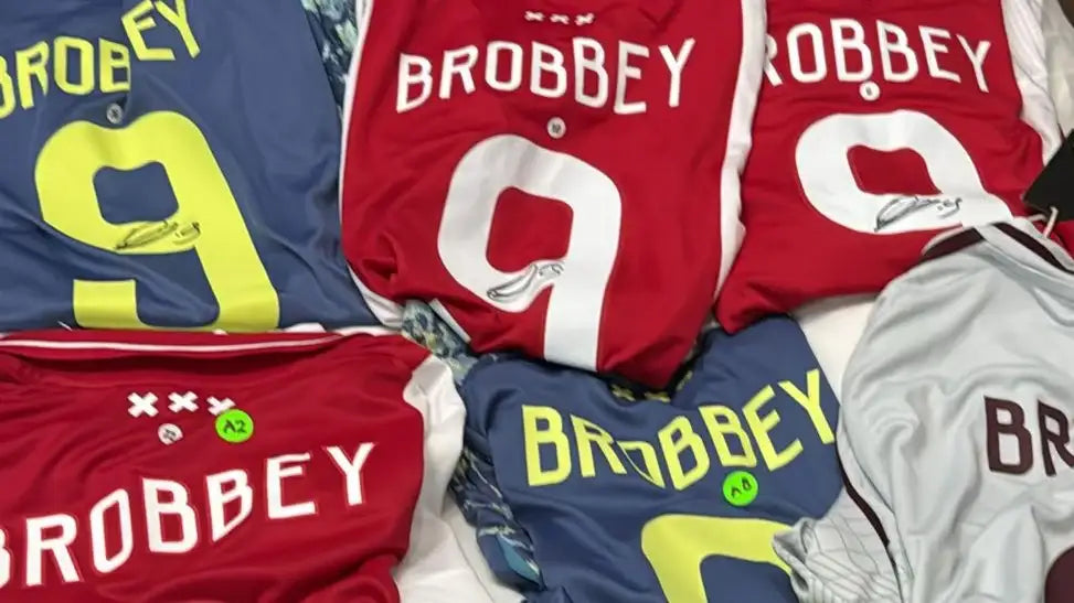 Collection of Ajax home and away football shirts with 'BROBBEY' branding.