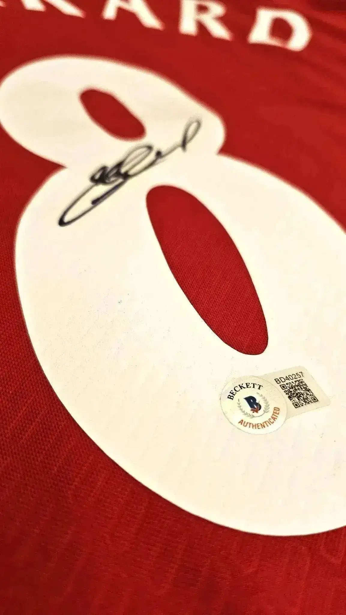 Detail showing the signature of Gerrard on the No. 8 of the Liverpool soccer jersey.