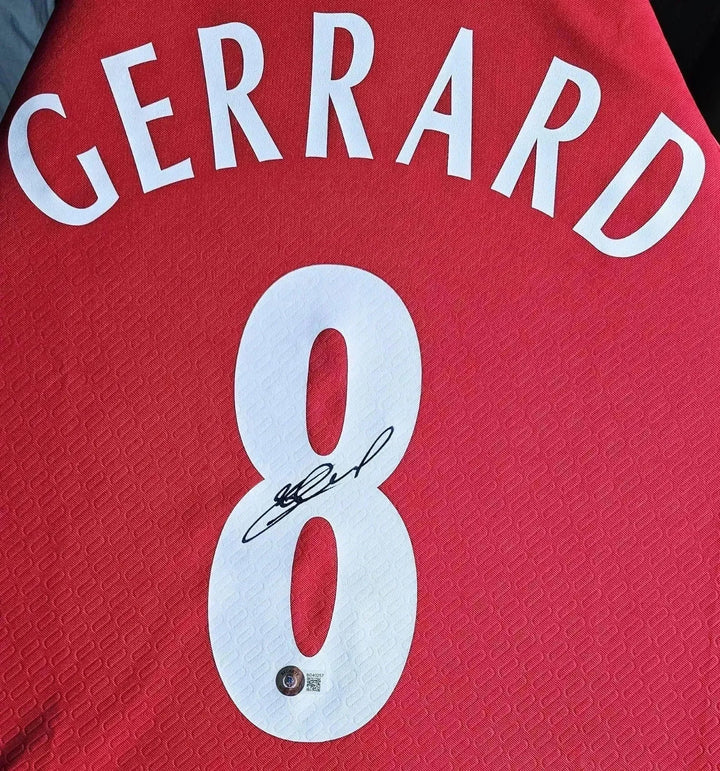 Back view showing Gerrard, No. 8 with visible signature on red football shirt.