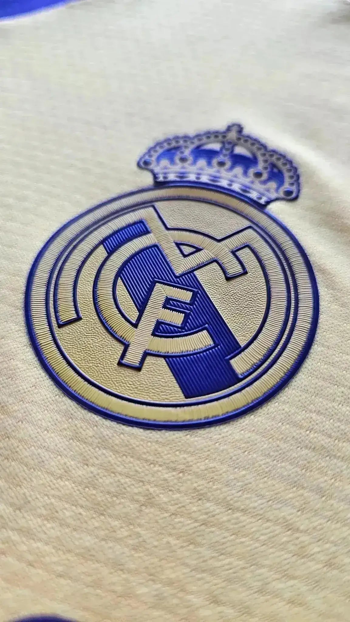 Close-up of Real Madrid crest in blue and gold, featuring the royal crown.