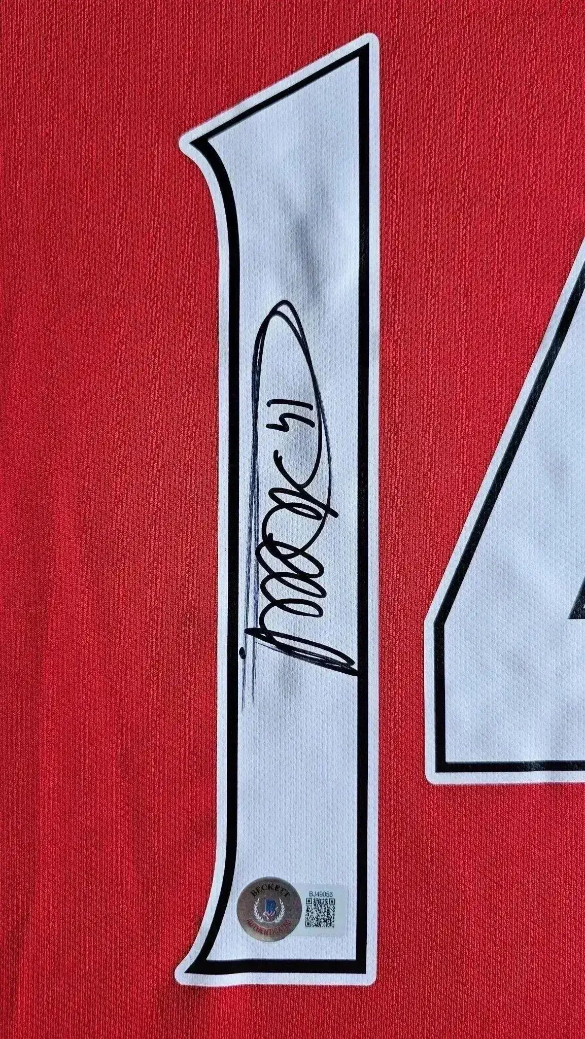 Detail view showing signature of Thierry Henry on No. 14 Arsenal soccer jersey.