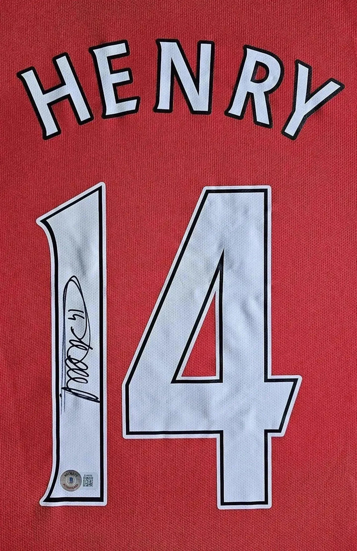 Back view showing name 'HENRY', No. 14, and signature on red football shirt.