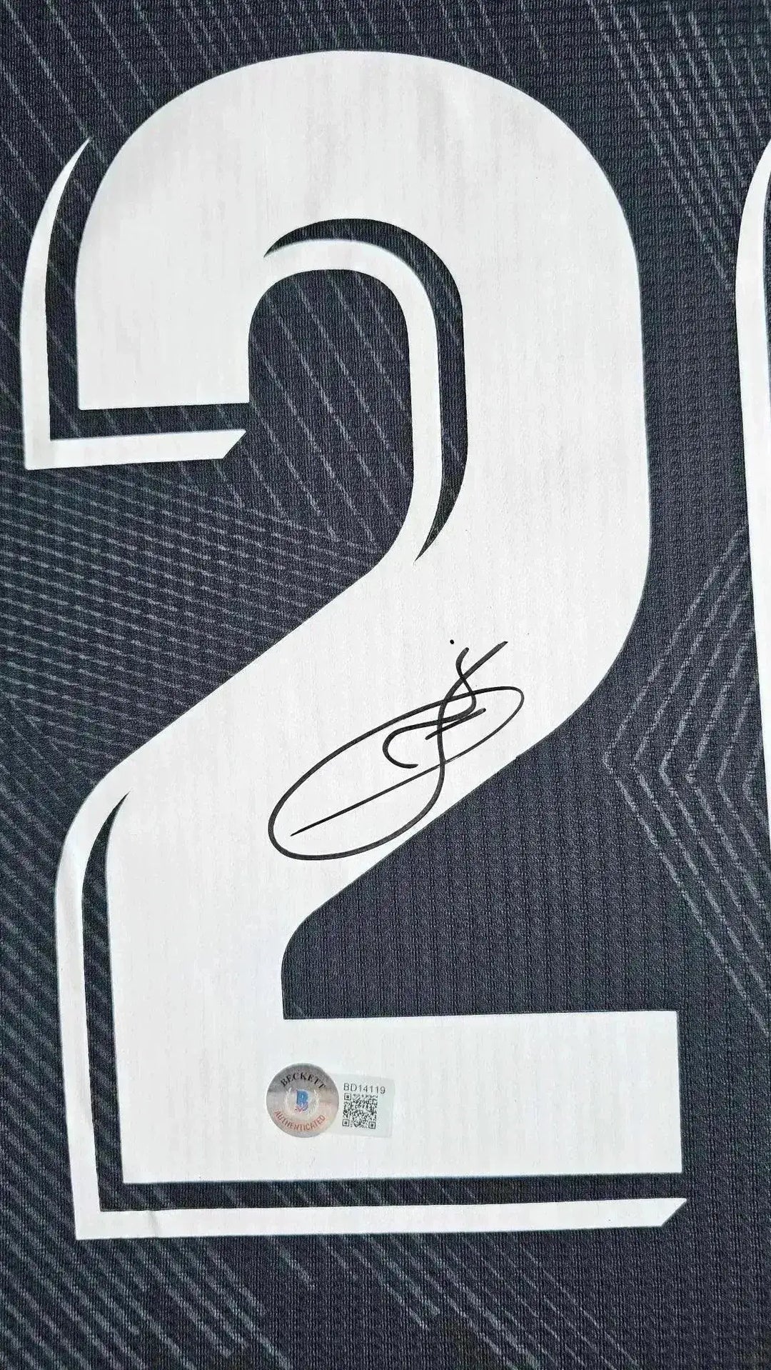 Detail showing No. 20 and signature on Vinicius Jr's soccer jersey.