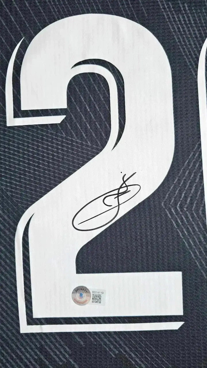 Detail showing No. 20 and signature on Vinicius Jr's football shirt.