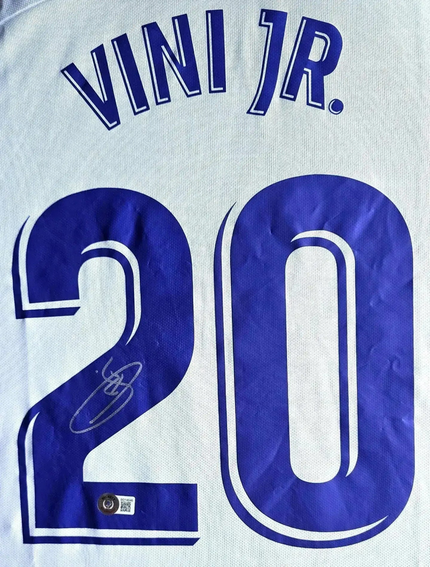Detail of signed shirt showing the name 'VINI JR.' and number '20' with a visible signature.