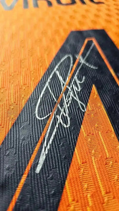 Close-up of signature on orange football shirt with black detailing.