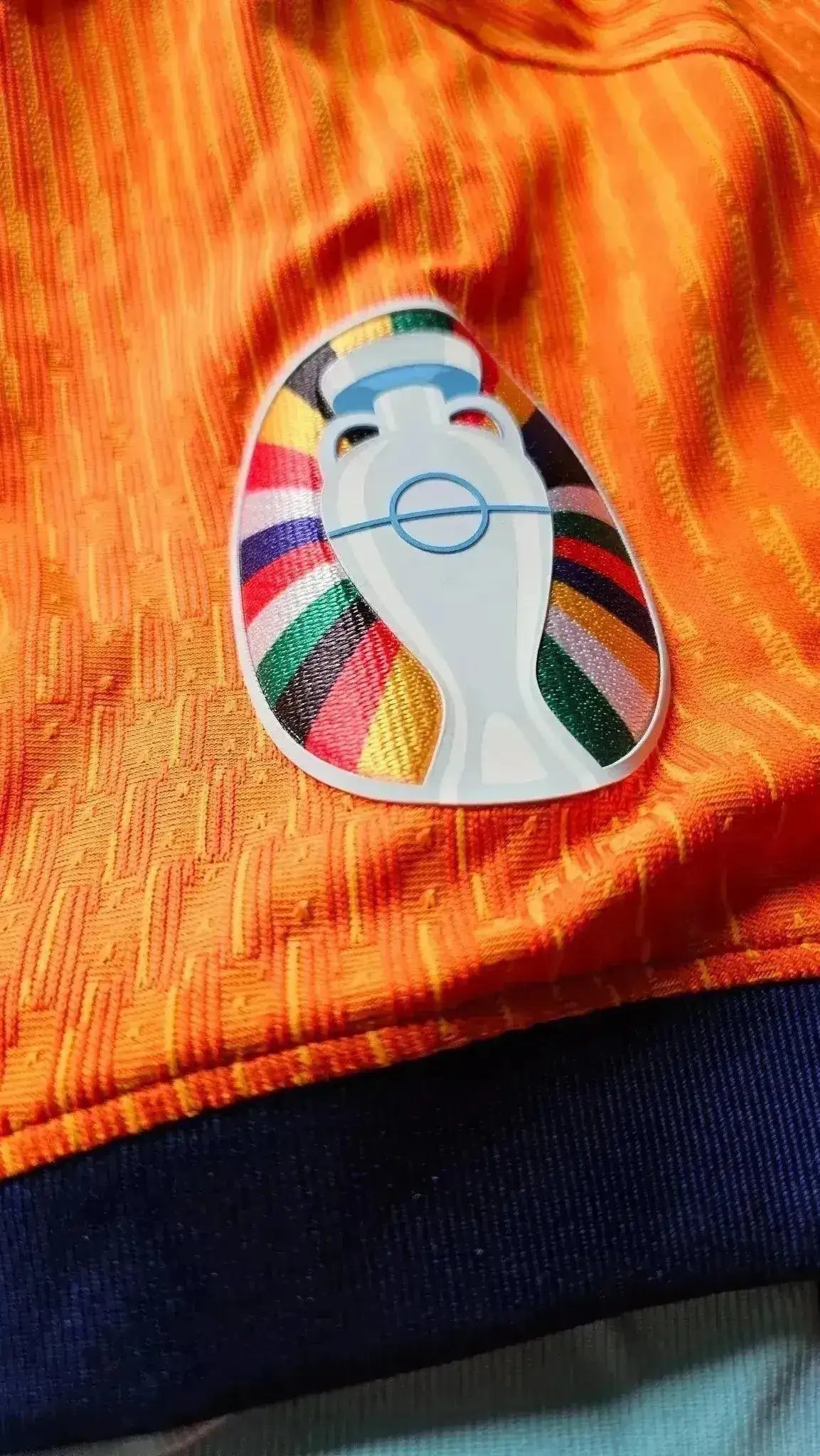 Crest detail featuring the colorful UEFA Euro logo on an orange football shirt.