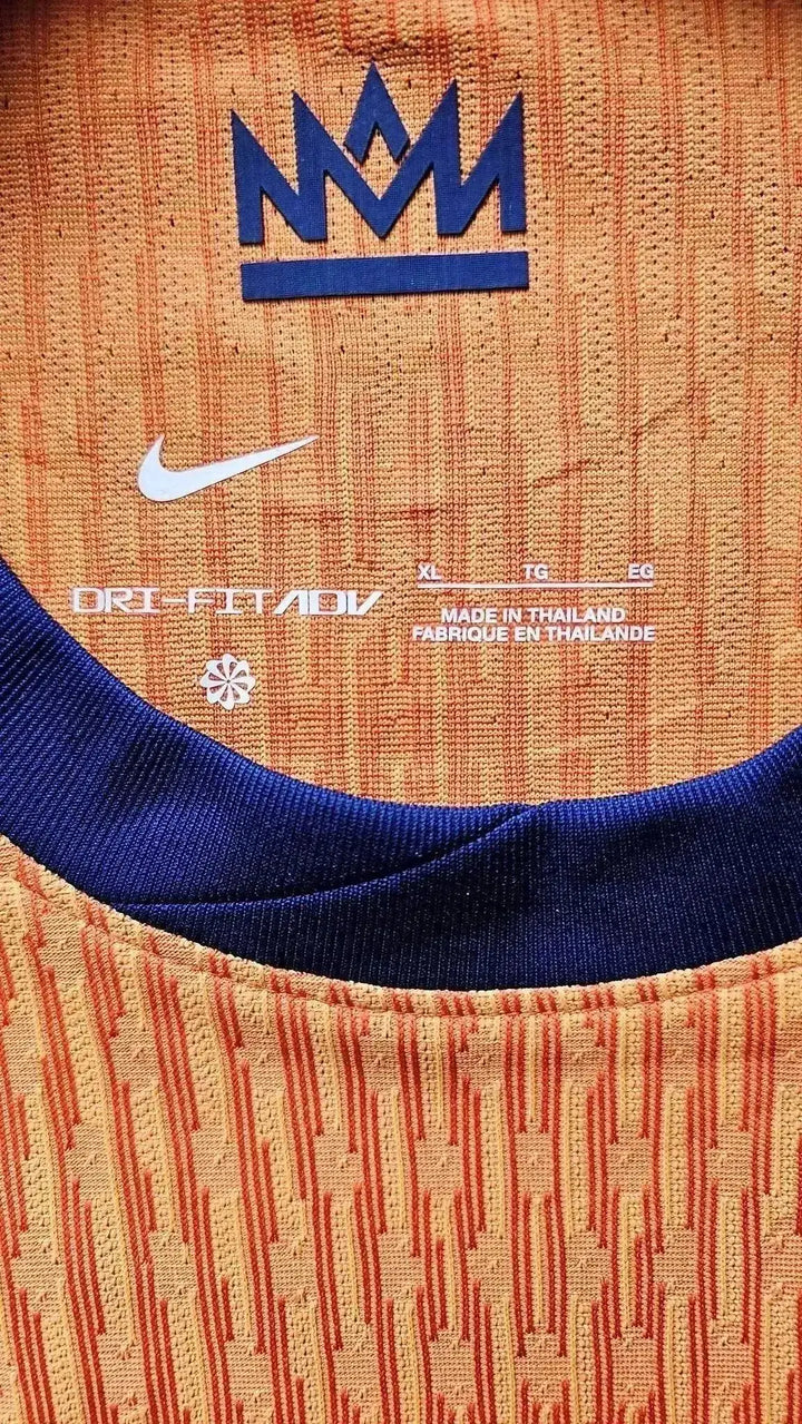 Close-up showing Nike logo, DRI-FIT ADV text, and care label details in orange and blue.