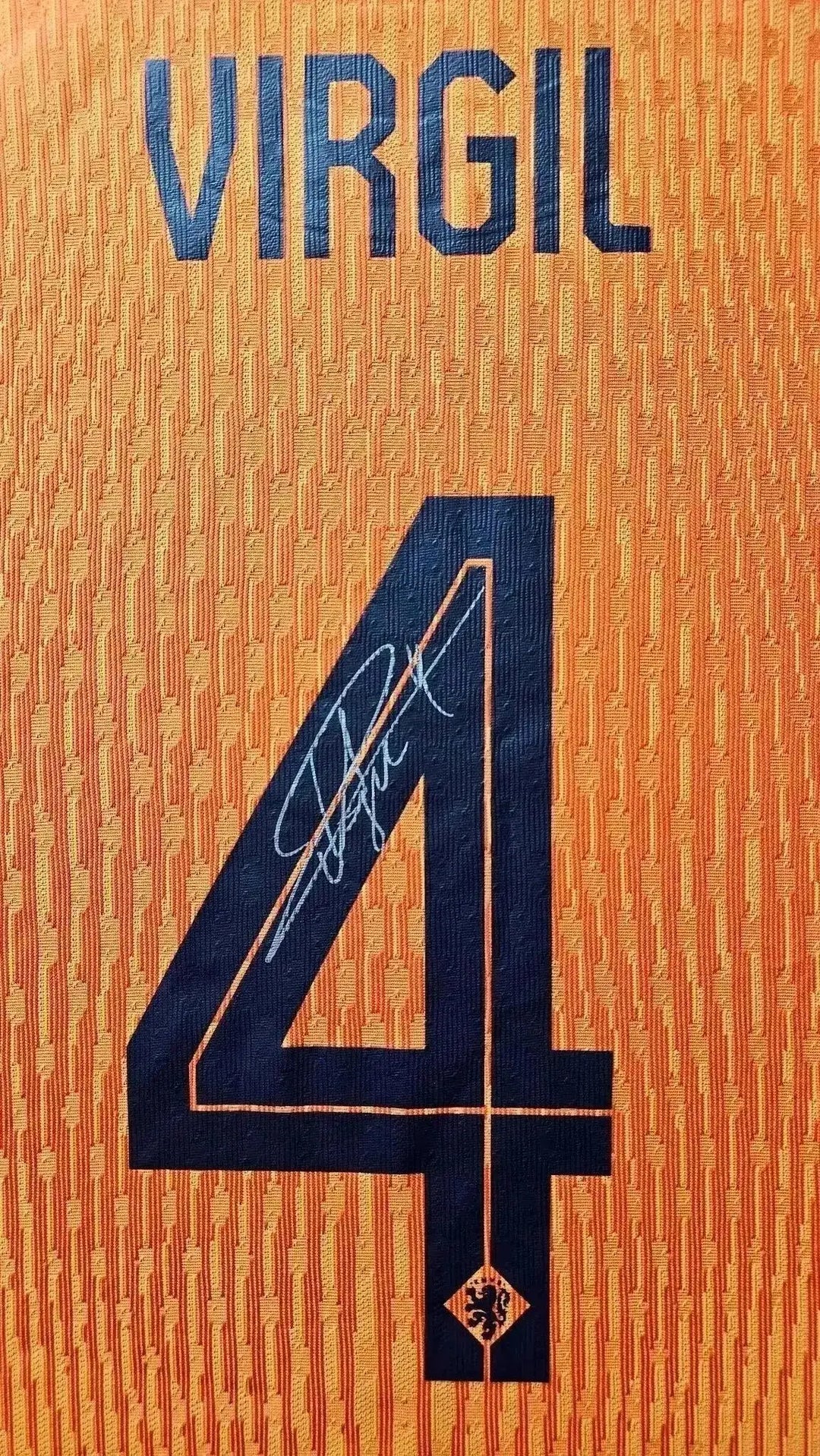 Detail showing signature and No. 4 on vibrant orange football shirt with VIRGIL printed above.