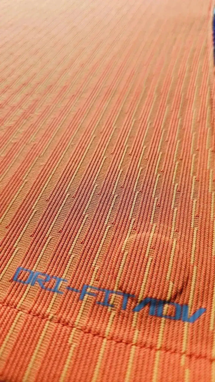 Close-up showing DRI-FIT label on the textured orange football shirt.