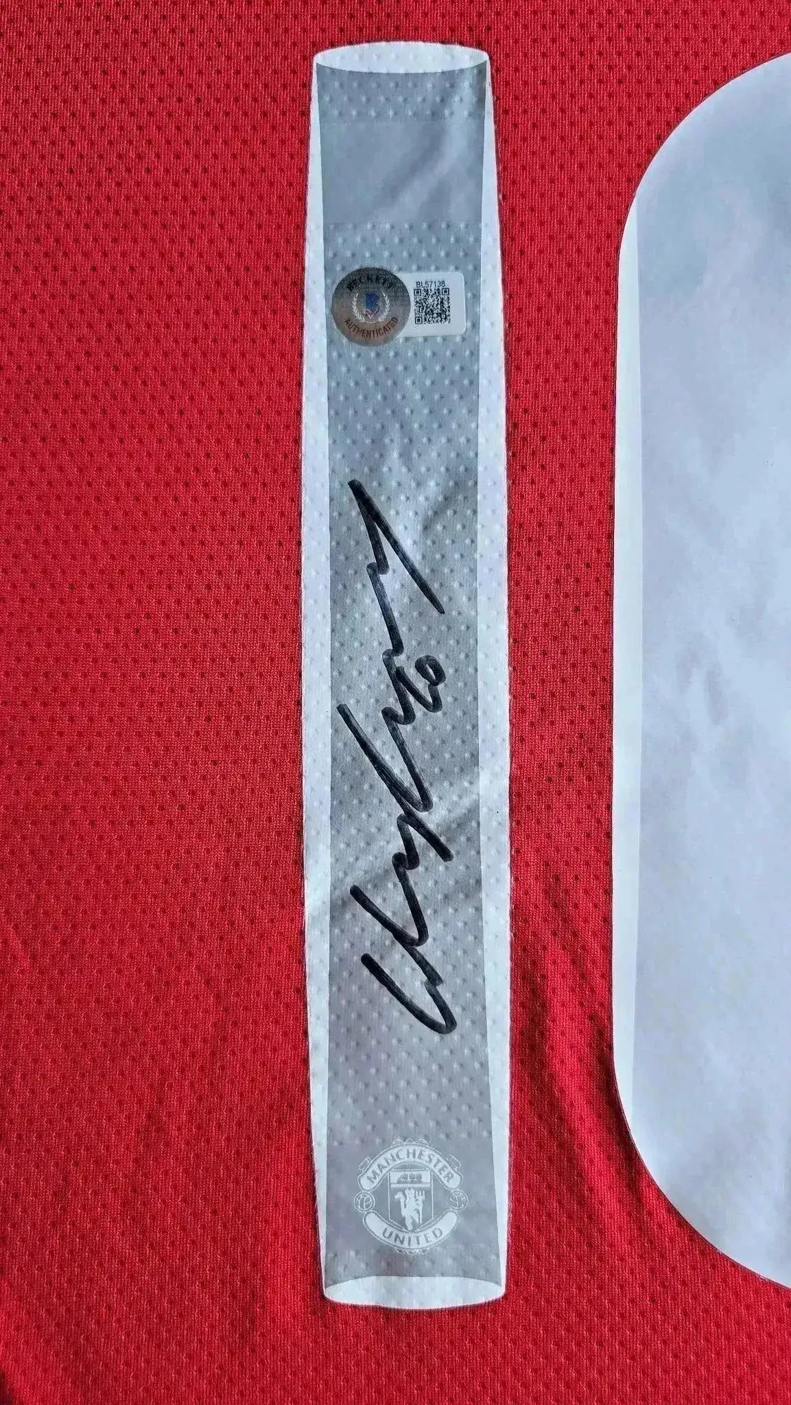 Signature detail of Wayne Rooney on Manchester United soccer jersey with club crest.