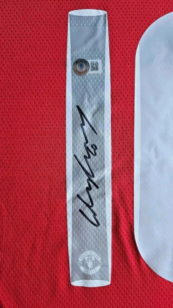 Signature detail of Wayne Rooney on Manchester United football shirt with club crest.