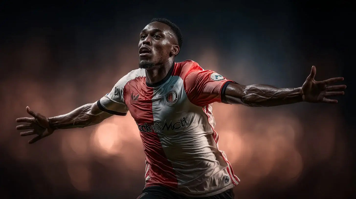 Antoni Milambo of Feyenoord celebrating with arms wide, red and white home shirt, side profile under soft stadium lights.