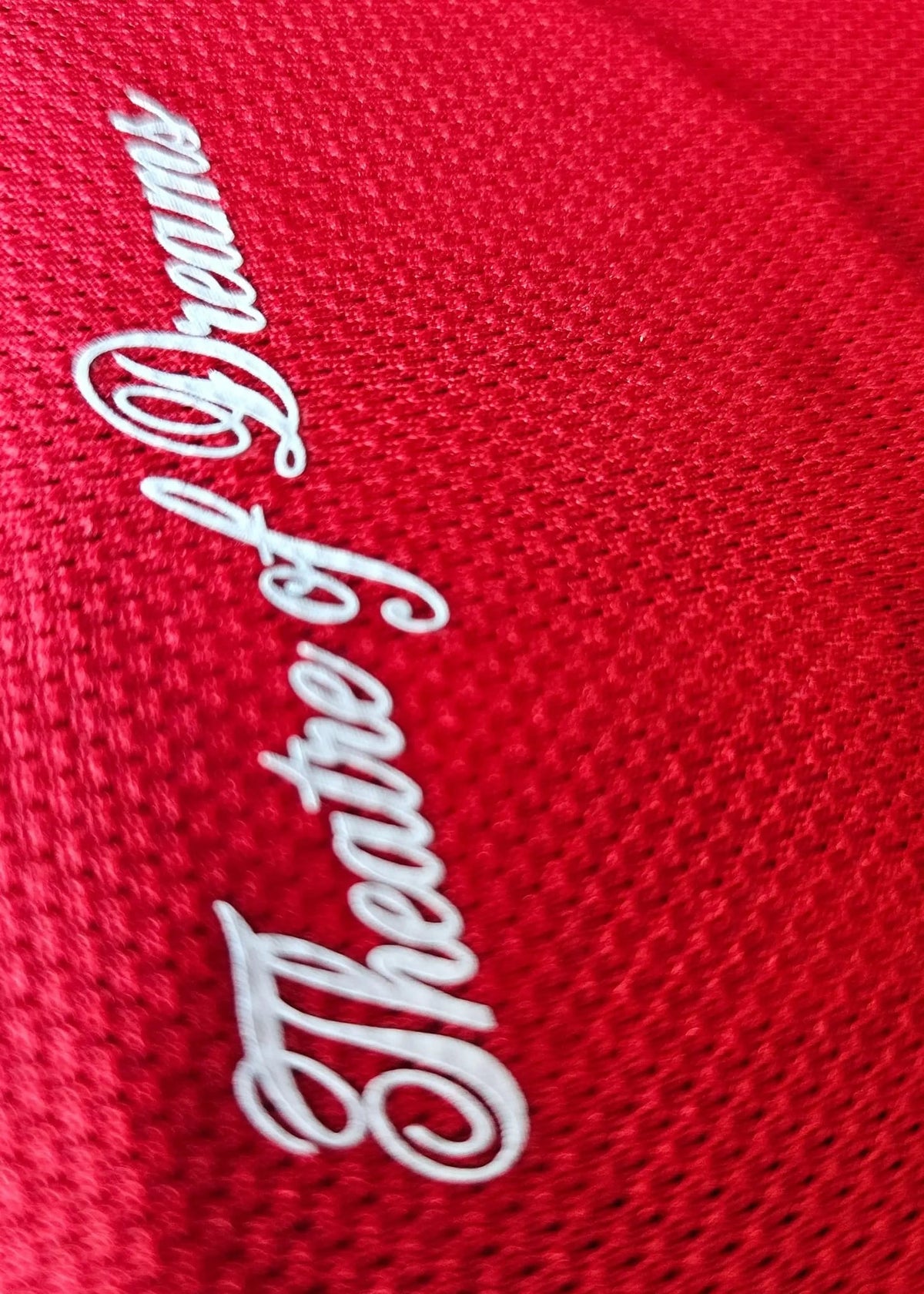 Close-up of the white cursive Theatre of Dreams script at the collar of Bendito Mantato's red Manchester United F.C. shirt, No. 70, 2025-2026.