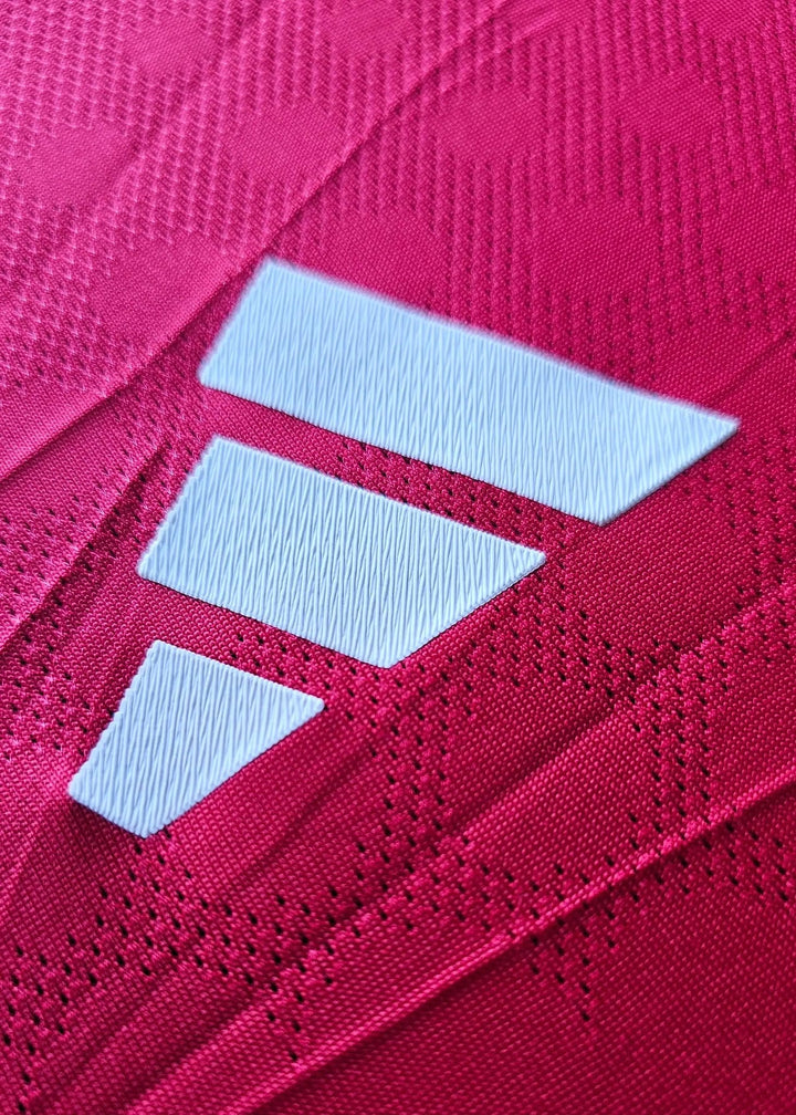 Close-up of detail showing the white insignia on the red fabric of the football shirt.