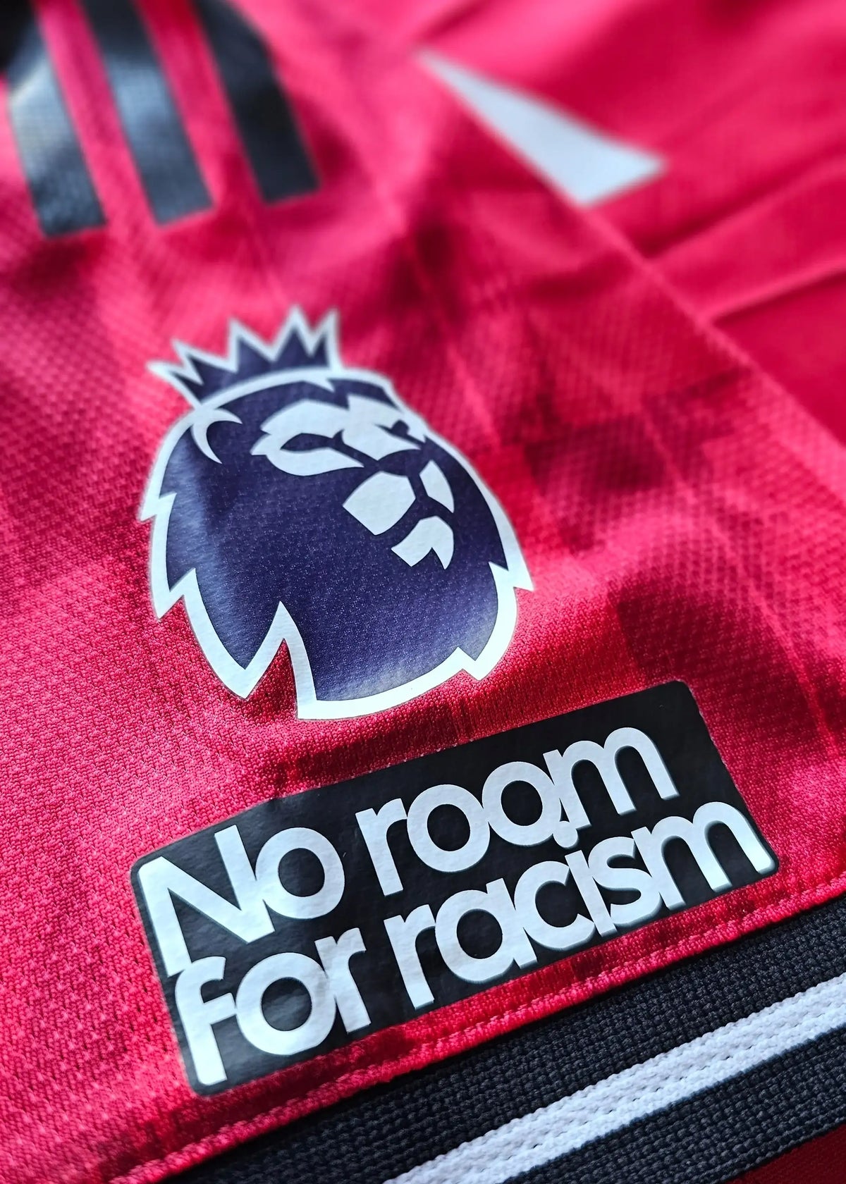 Close-up of the Premier League crest and No room for racism patch above the cuff on Bendito Mantato's red Manchester United F.C. shirt, 2025-2026.