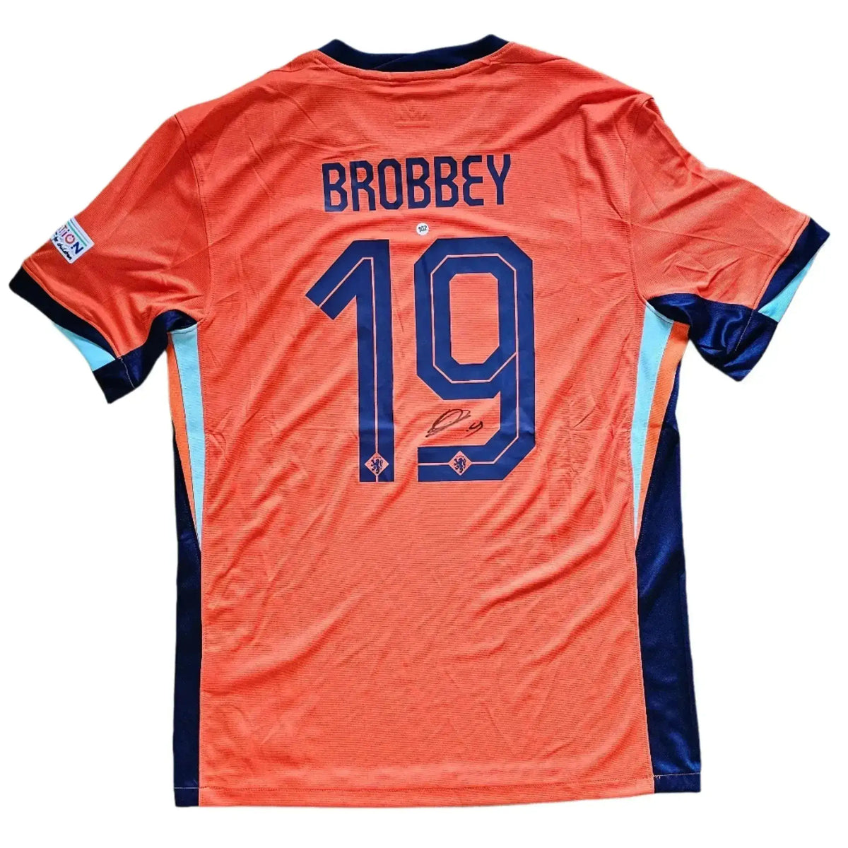 Orange Netherlands shirt back, printed BROBBEY 19 in navy above the KNVB crest, with a marker signature beneath the number; Euro 2024 home kit.