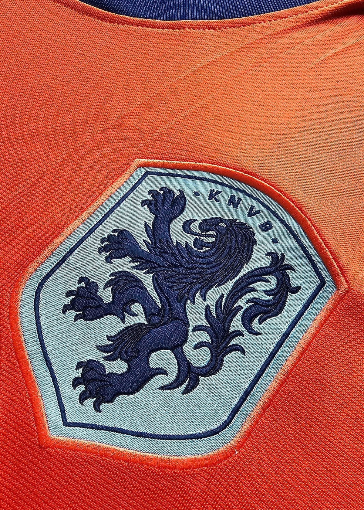 Embroidered KNVB Netherlands crest, a rampant navy lion on a pale blue hexagonal shield, on the chest of Brian Brobbey's orange Holland shirt, No. 19.