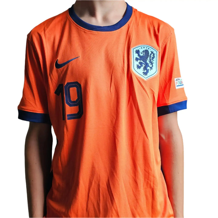 The Nike swoosh, navy KNVB lion crest, and number 19 on the front of Brian Brobbey's orange Netherlands shirt, with a UEFA Foundation sleeve patch.