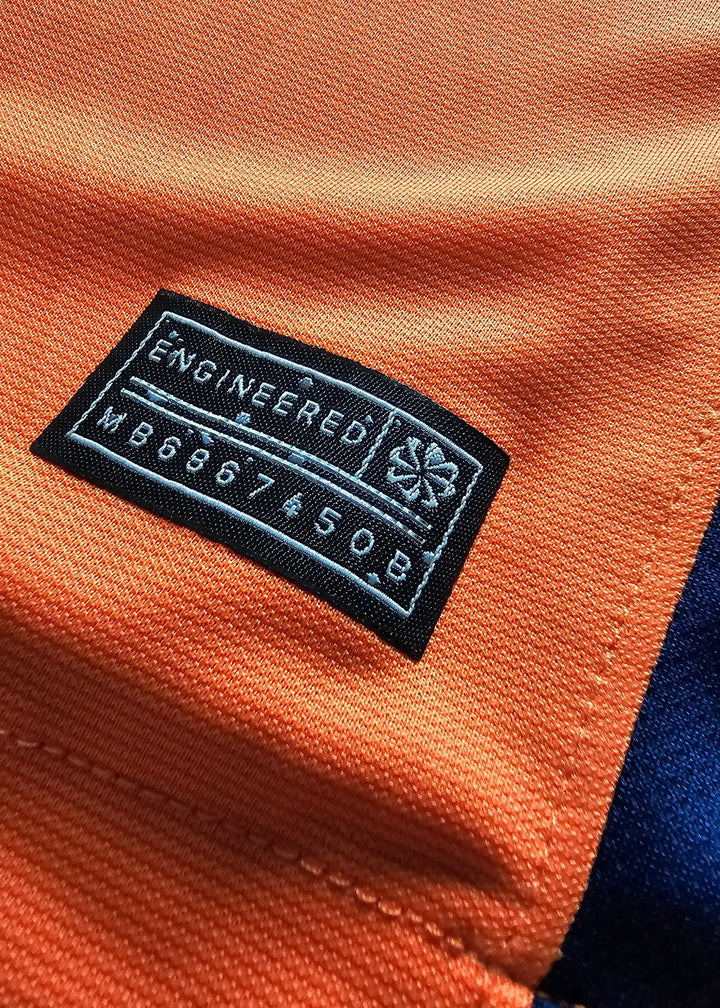 Close-up of an inner 'Engineered' size and care label stitched into the collar seam of Brian Brobbey's orange Holland shirt, No. 19.