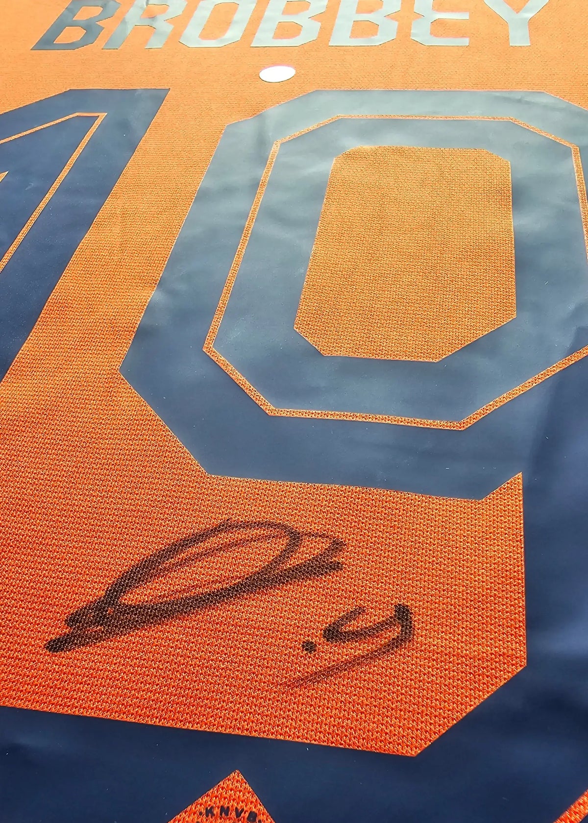 A black-ink signature written across the navy number on the back of Brian Brobbey's orange Netherlands shirt, from his signed Euro 2024 shirt.