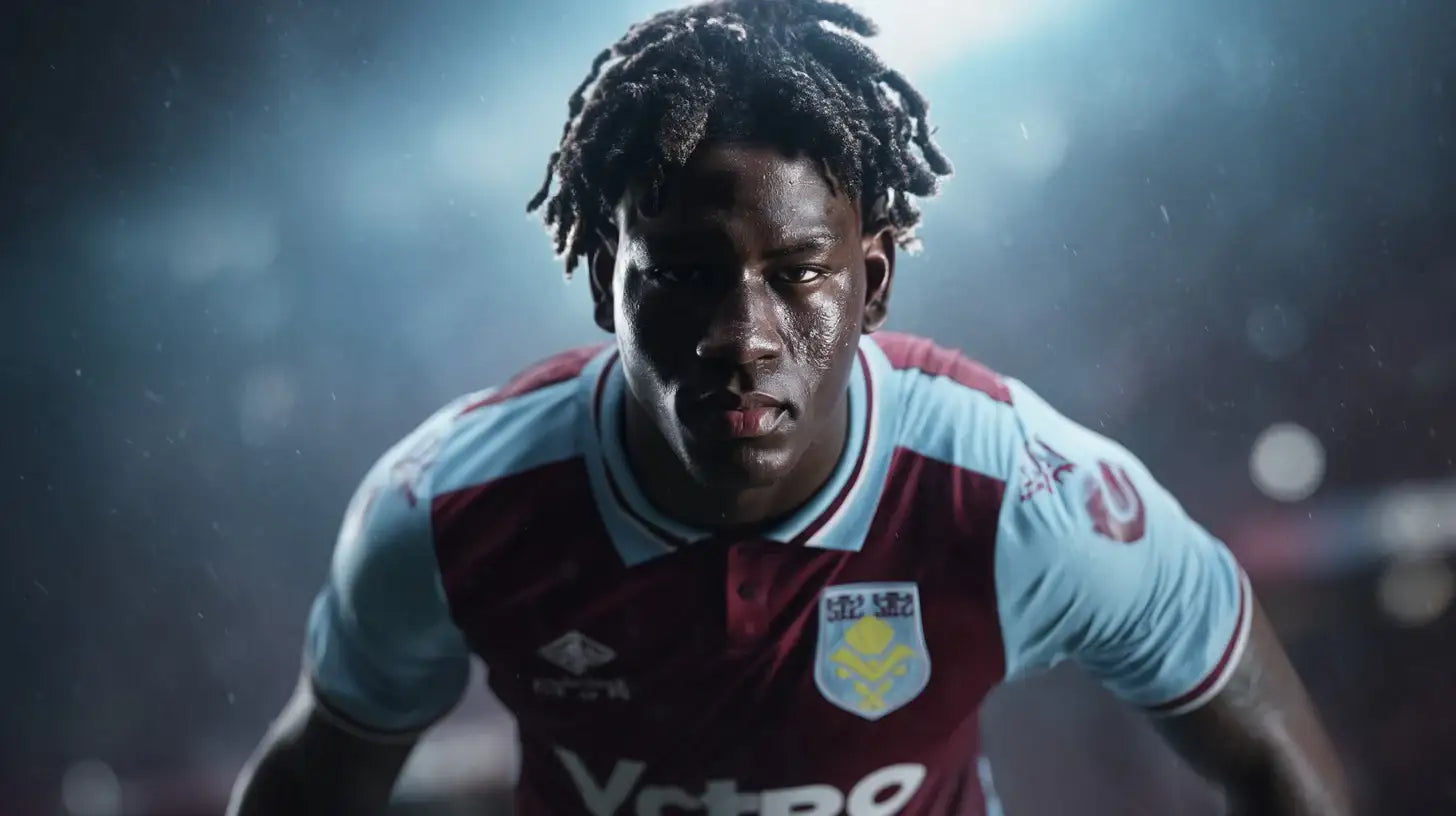 Brian Madjo in Aston Villa claret and light blue football shirt, intense close-up in rainy stadium setting.