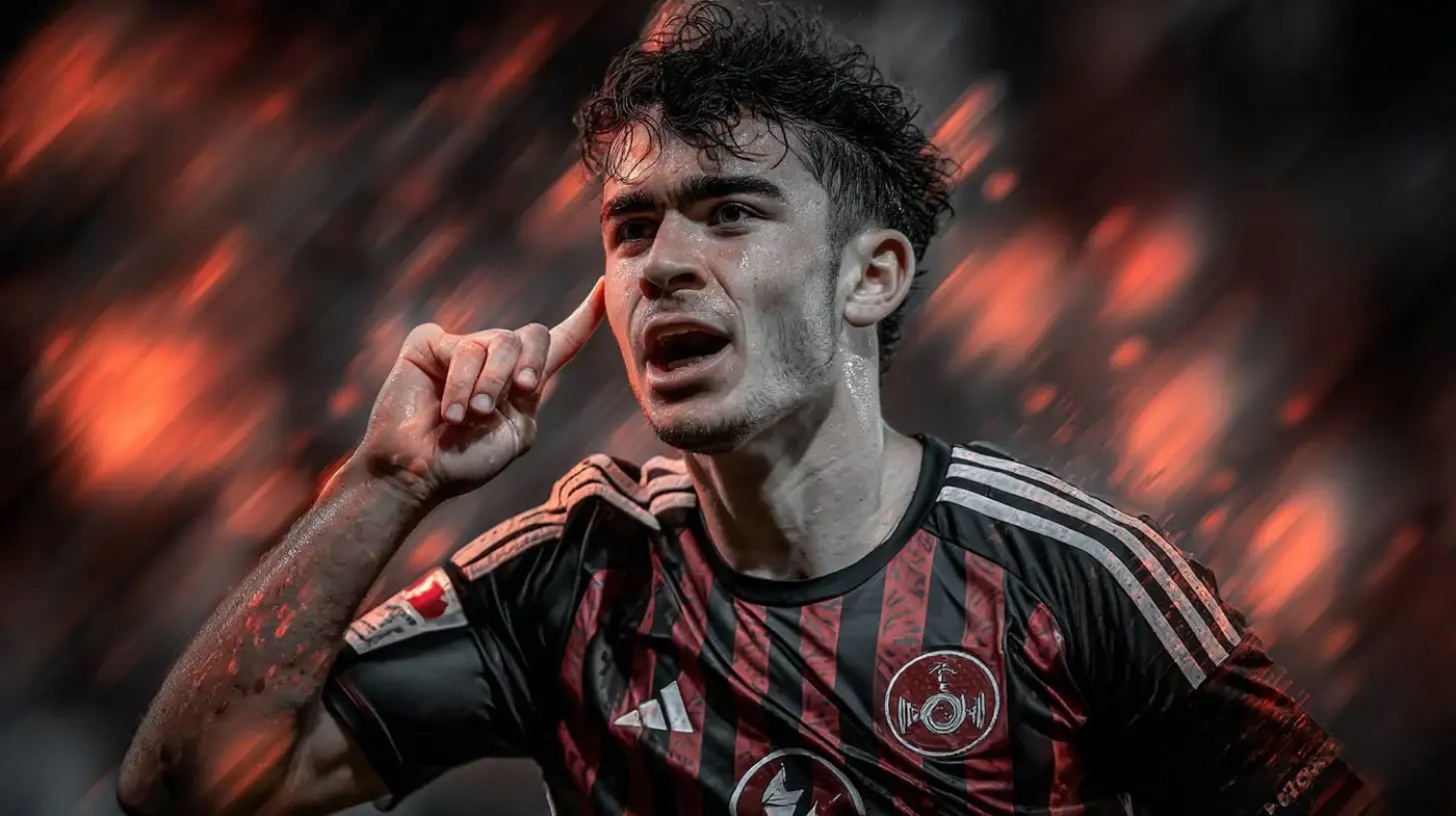 Can Uzun shouting and pointing to his ear in an Eintracht Frankfurt away kit with blurred lights.