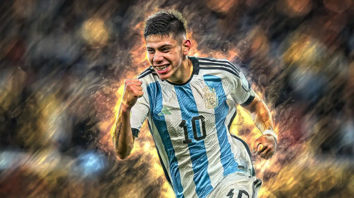 Claudio Echeverri celebrates with a clenched fist in Argentina’s sky-blue and white number 10 football shirt, smiling under bright stadium lights with motion blur behind.