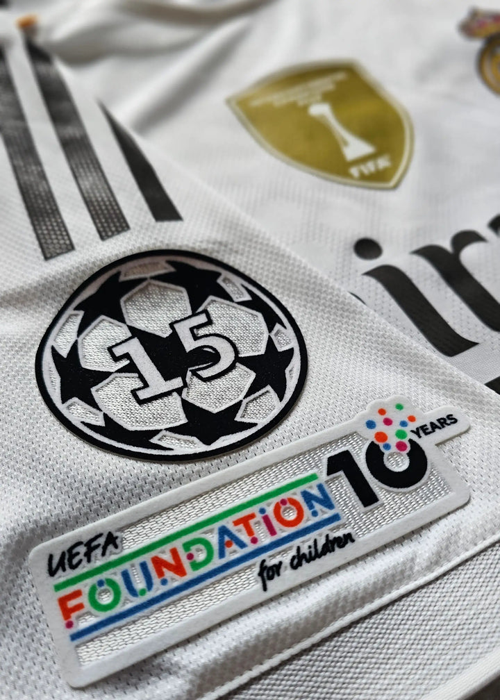 Close-up of the sleeve patches on the Real Madrid shirt: the UEFA Champions League 15th-anniversary badge and UEFA Foundation emblem.