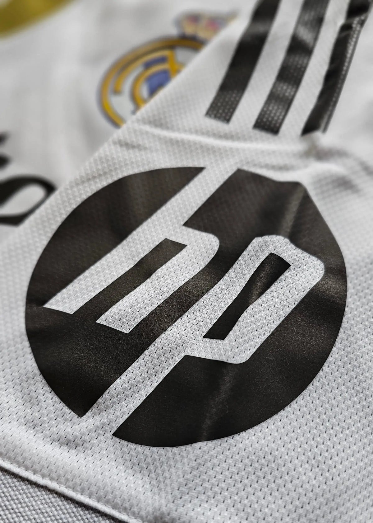 Detail showing the black HP logo and Real Madrid crest on a white football shirt.