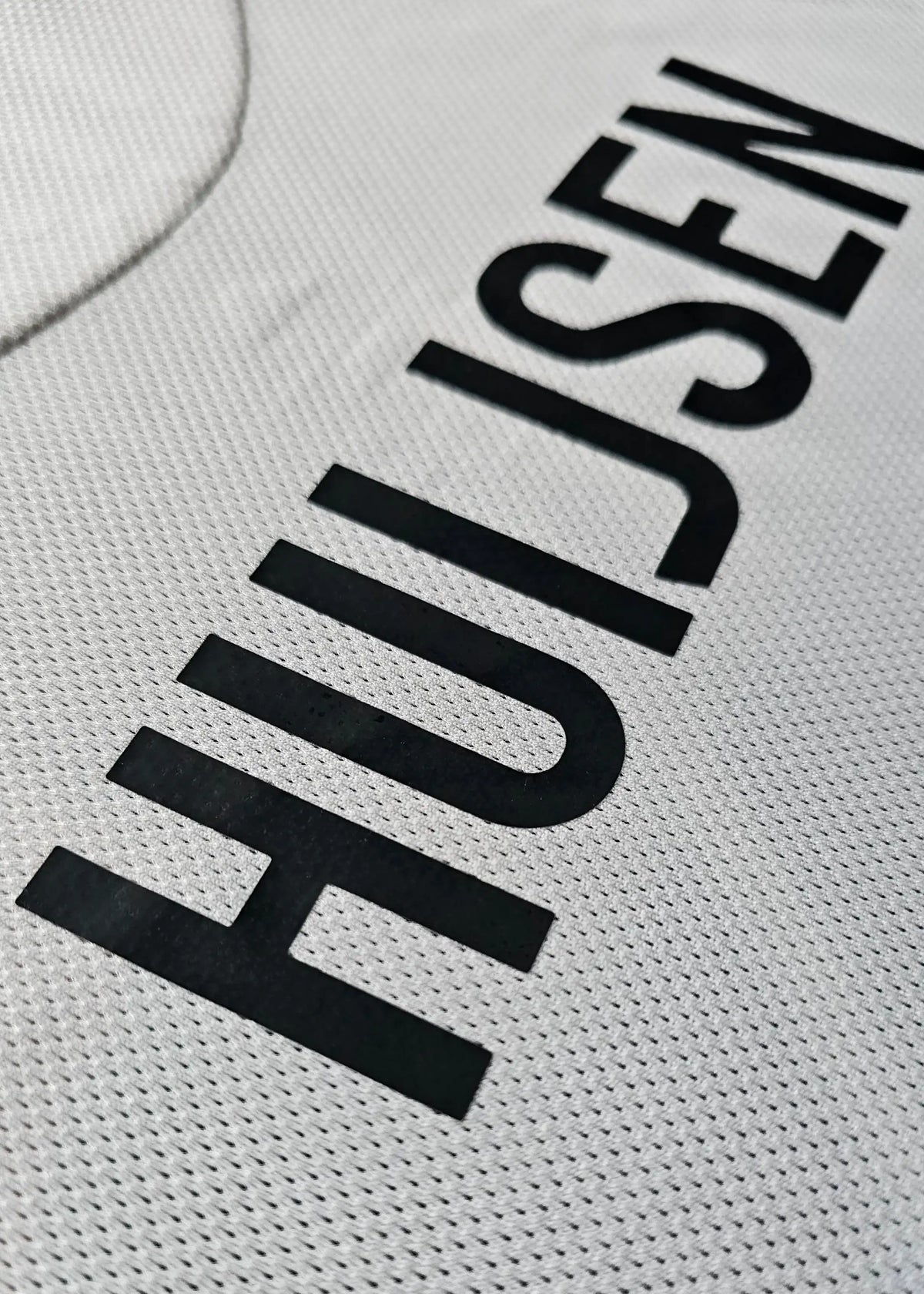 Close-up detail showing the name 'HUIJSEN' in bold black lettering on a white football shirt.