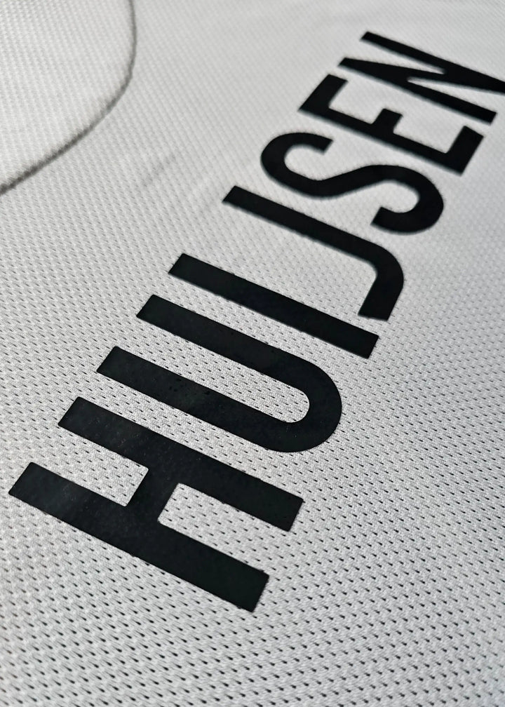 Close-up detail showing the name 'HUIJSEN' in bold black lettering on a white football shirt.