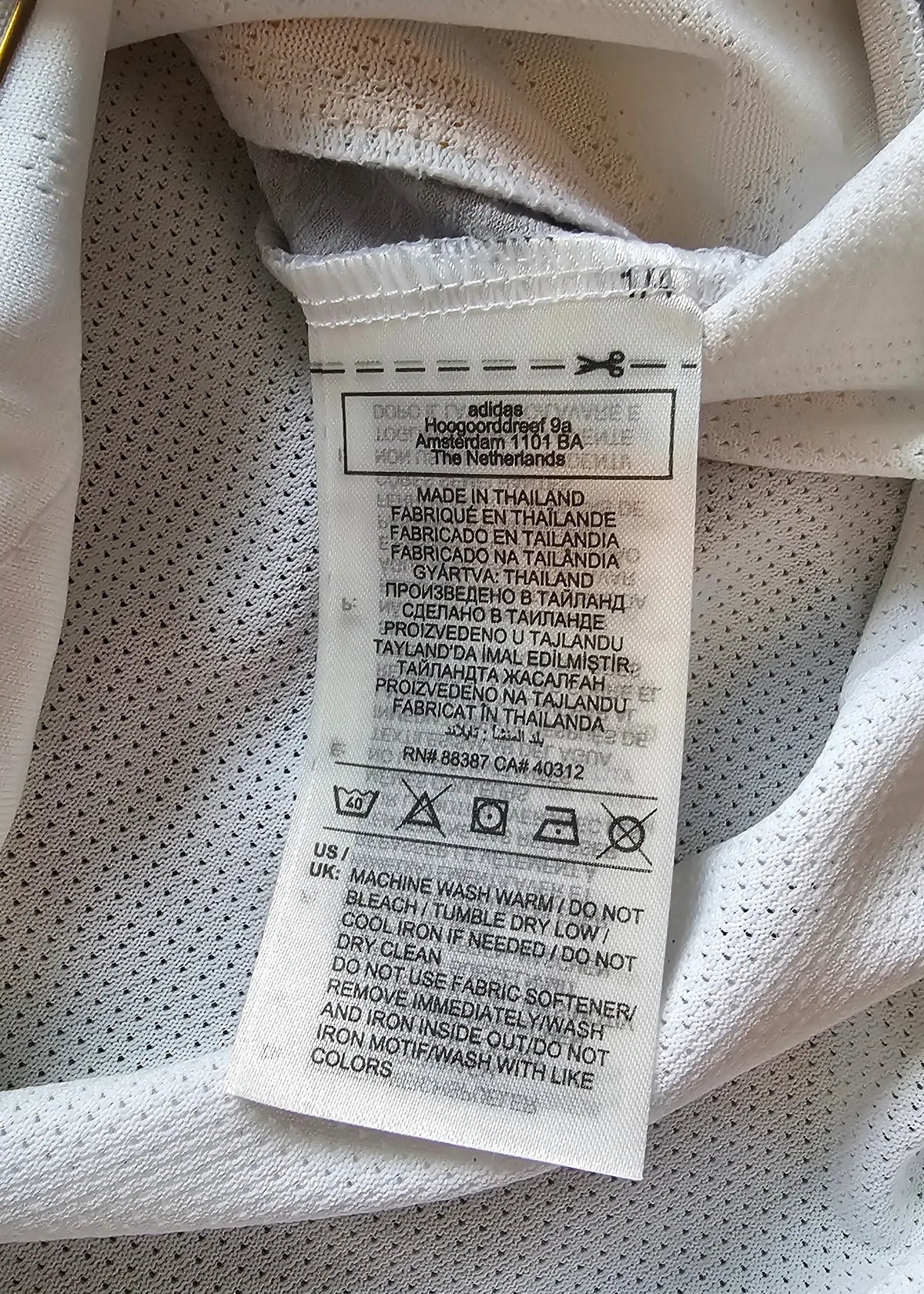 Close-up of the Real Madrid shirt's care label, listing adidas's Amsterdam address and wash instructions.