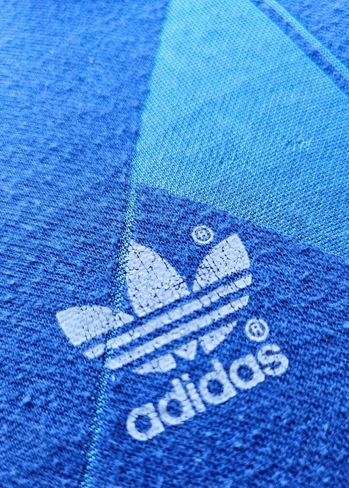 Embroidered adidas trefoil logo with the adidas wordmark, stitched onto the blue fabric of Eike Immel's West Germany 1987-88 shirt.