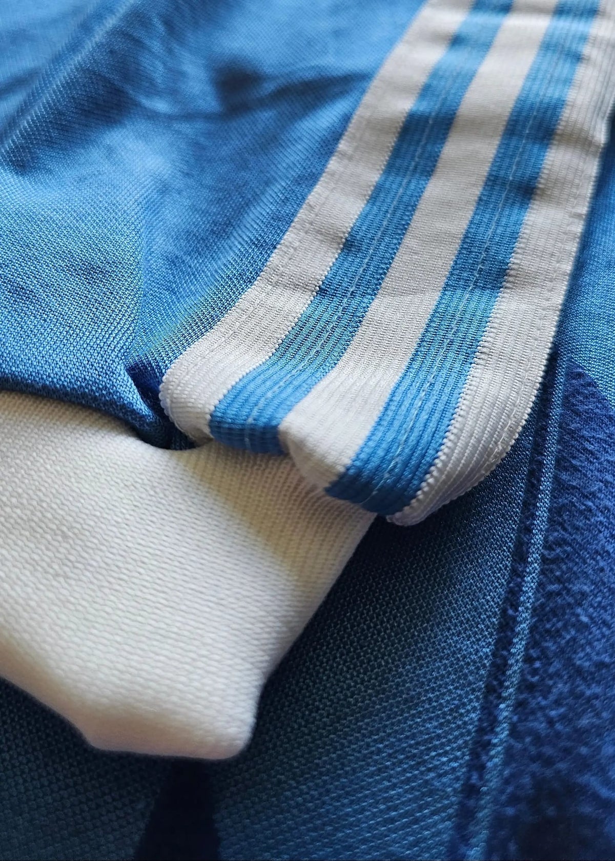 Close-up of the white adidas three-stripe trim folded against the blue sleeve of Eike Immel's West Germany 1987-88 shirt.