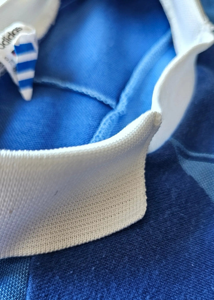 Close-up of the ribbed white collar and shoulder seam, with a small adidas trefoil tag stitched at the neckline of Eike Immel's West Germany 1987-88 shirt.
