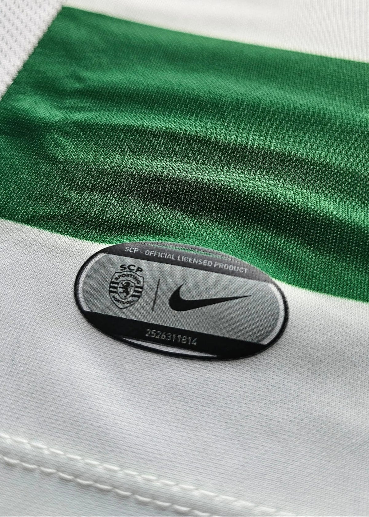 Close-up of a green and white striped athletic jersey with a black oval Nike patch reading 'SCA Official Licensed Product' on the white fabric.