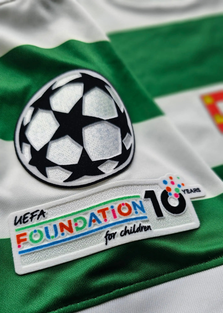 Close-up of a green and white striped soccer jersey featuring the UEFA Champions League patch and a UEFA Foundation for Children 10 Years patch.
