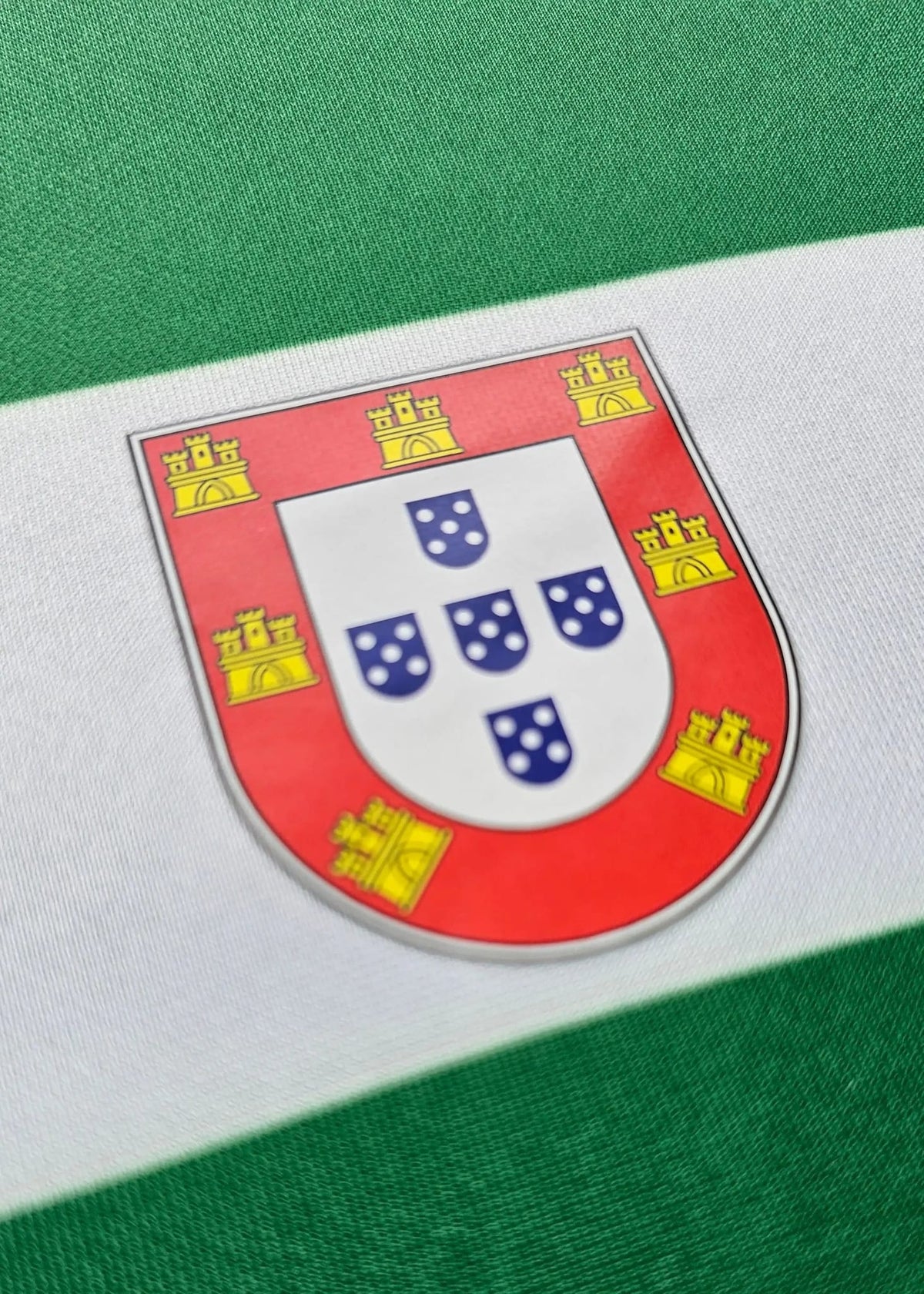 Detail of a shield patch bearing Portugal's historic castles and quinas design on the shirt sleeve.
