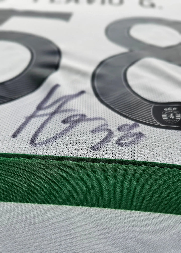 Close-up of a white soccer jersey with a green horizontal band, large dark gray number 58, and a dark signature on the front.