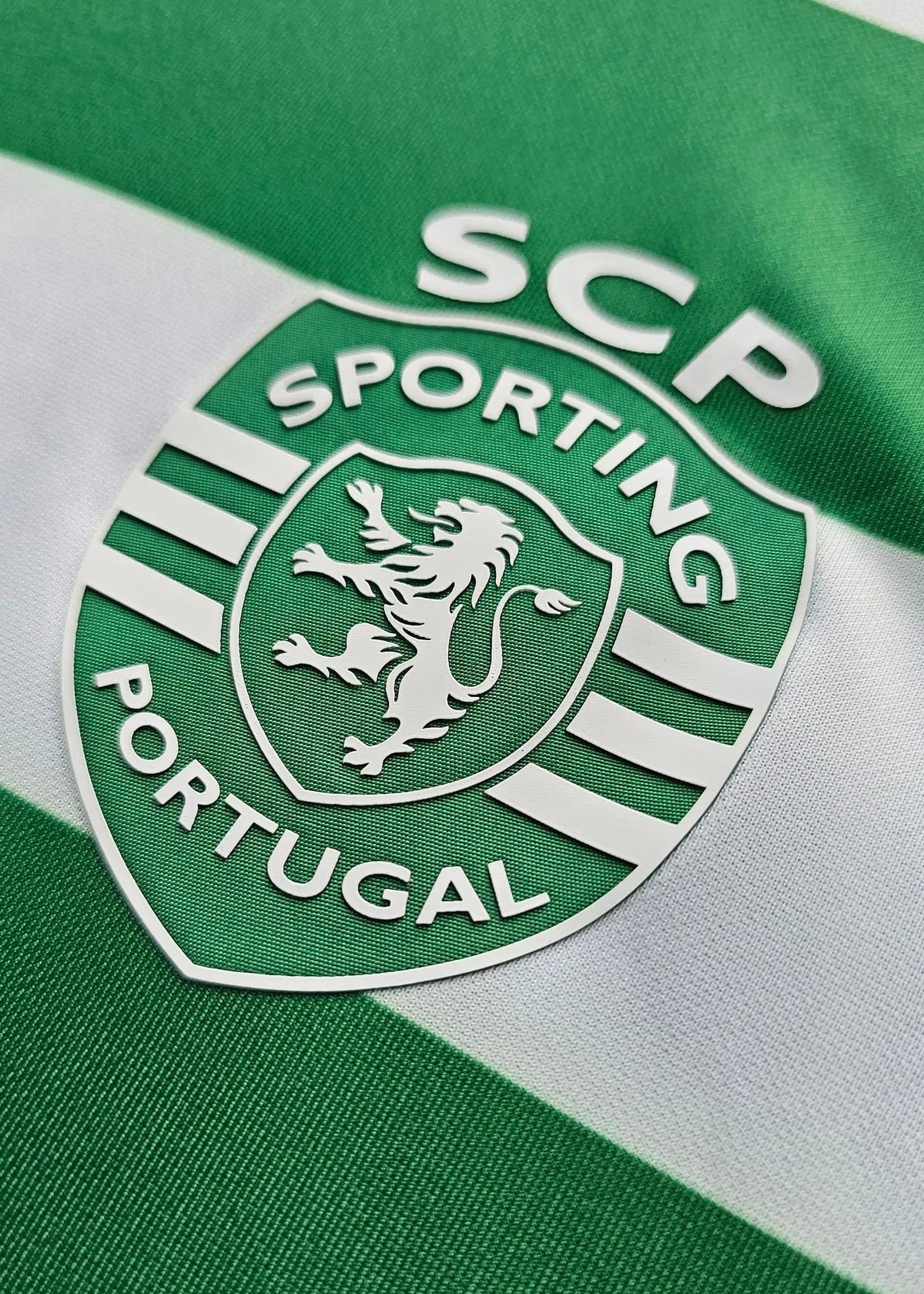Close-up of a green and white striped Sporting Portugal jersey with the club crest and 'SCP' lettering.
