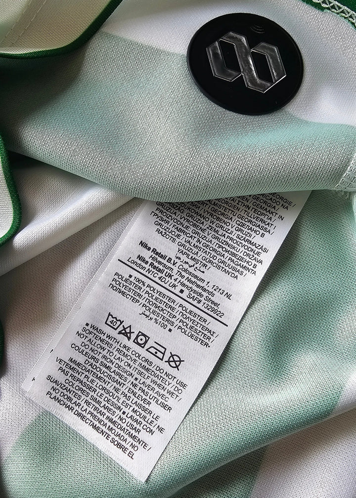 Close-up of the mint green and white shirt's interior lining, a black button with a silver logo, and a care label.