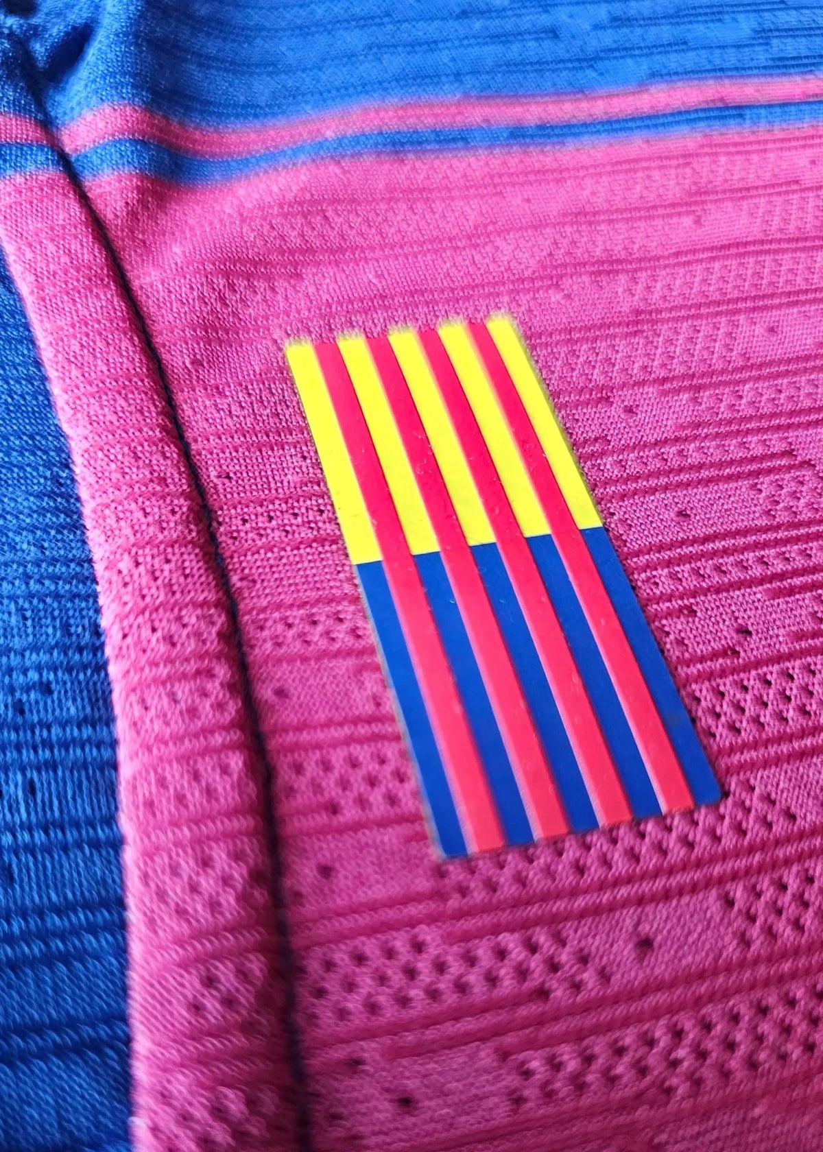 Red-yellow-blue Catalan senyera stripe patch stitched onto the pink-and-blue fabric of Frenkie de Jong's FC Barcelona 2025-2026 shirt.