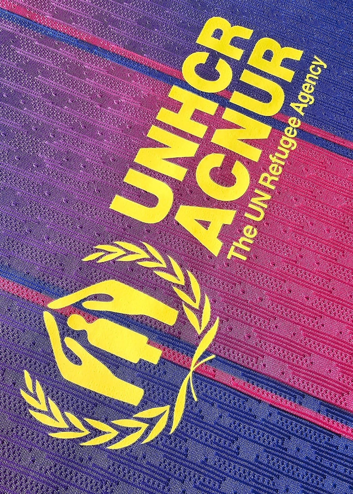 Yellow 'UNHCR ACNUR, The UN Refugee Agency' sponsor print with an olive-branch emblem, on the back of Frenkie de Jong's FC Barcelona shirt.