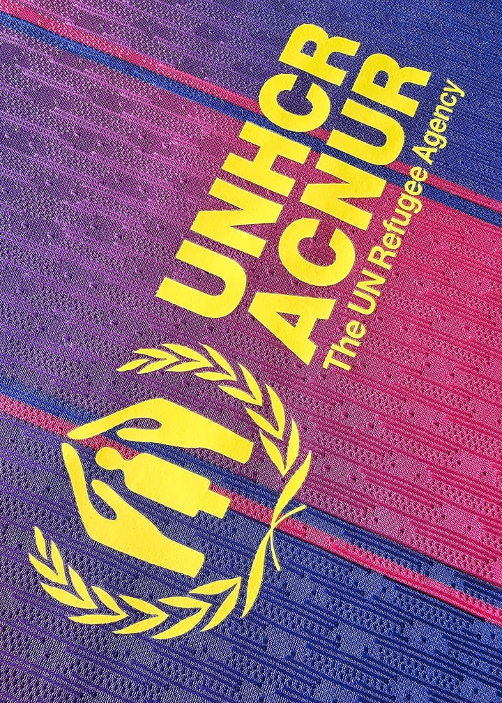 Yellow 'UNHCR ACNUR, The UN Refugee Agency' sponsor print with an olive-branch emblem, on the back of Frenkie de Jong's FC Barcelona shirt.
