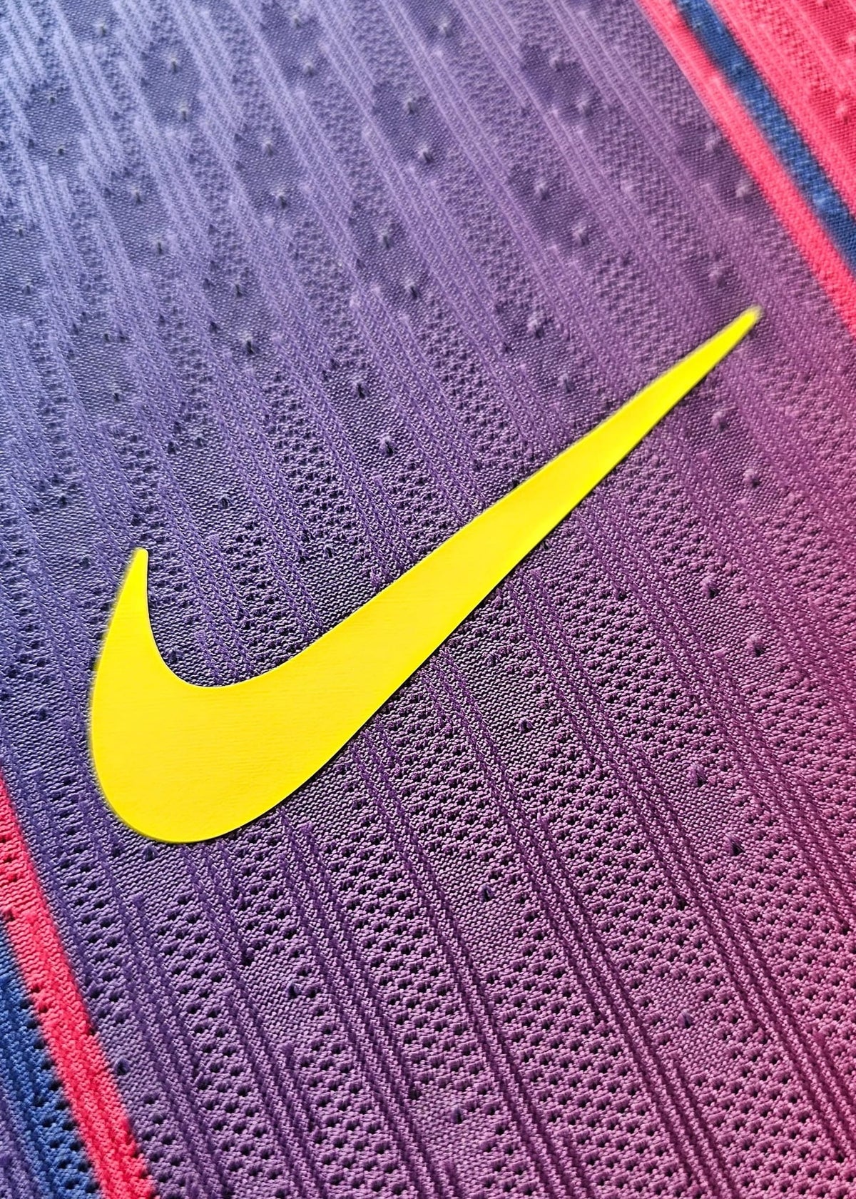 Yellow Nike swoosh printed on the purple-to-pink gradient fabric of Frenkie de Jong's FC Barcelona 2025-2026 football shirt.