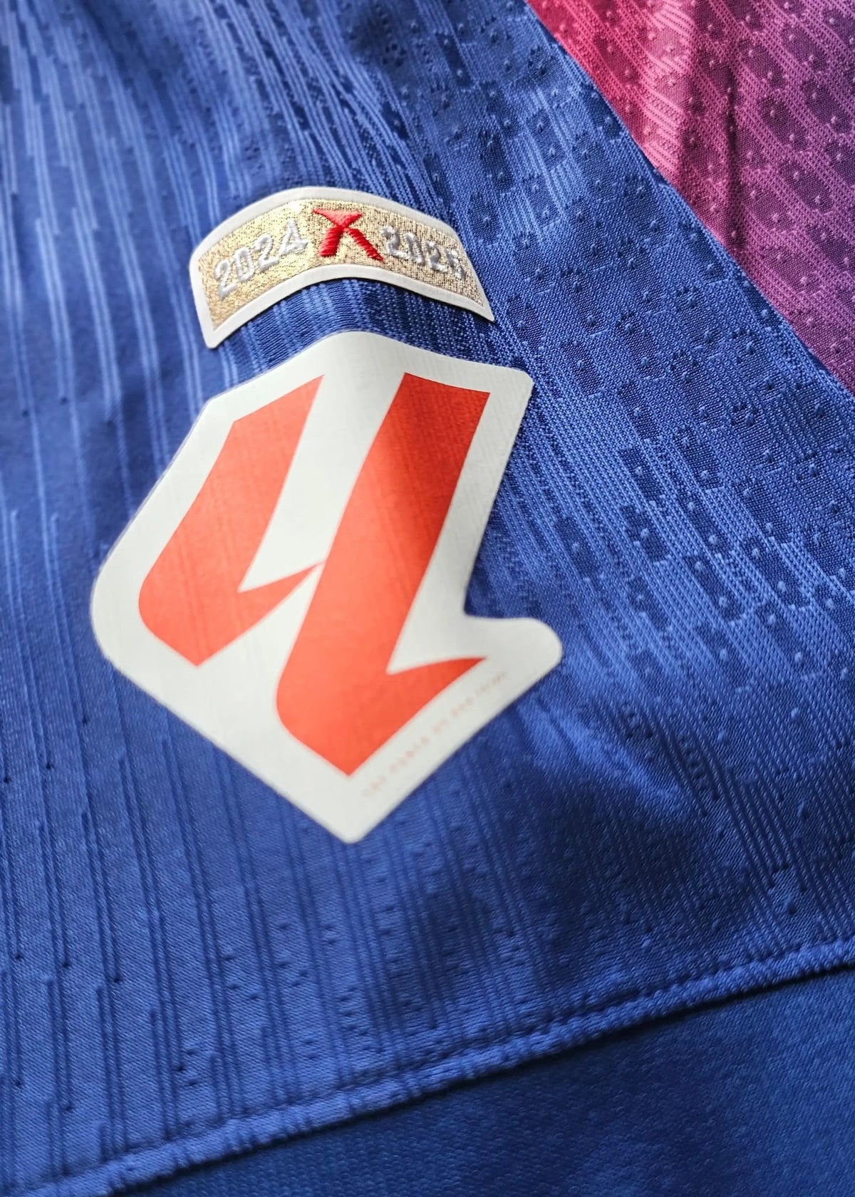 Orange-and-white competition badge below a '2024 X 2025' season tab, stitched on the navy sleeve of Frenkie de Jong's FC Barcelona shirt.