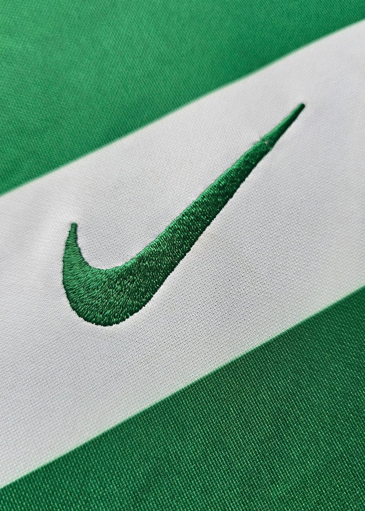 Embroidered Nike swoosh stitched into the green and white hooped fabric of Geovany Quenda's Sporting CP shirt.