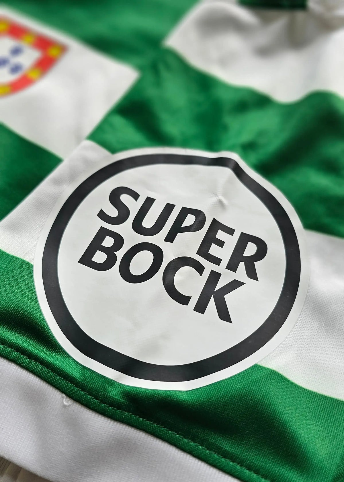 Super Bock sponsor patch on a green and white hooped shirt, with the chest crest visible in the corner, Geovany Quenda's Sporting CP shirt.